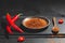 Red  chillies and chilli powder on wooden plate and spoon on blackboard base on black background. Gastronomy and cooking