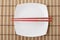 Red chopsticks and white dish on a bamboo napkin