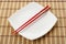 Red chopsticks and white dish on a bamboo napkin