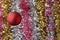 Red Christmas ball. Against the background of multicolored tinsel in blur.