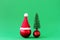 Red Christmas ball with Santa Claus red hat and shiny red ball with artificial Christmas tree on green background with copy space