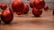 Red christmas balls falling on wooden table - slow motion