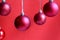 Red christmas balls hanging on a red background