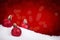 Red Christmas baubles on snow with a red background