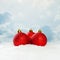 Red Christmas baubles on white snow background against blue sky with white clouds. Winter holidays concept