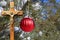 Red Christmas decoration hanging from outdoor tree with crucifix