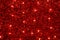 Red Christmas festive decorative background with tinsel, flashing lights. Wall illuminated by Christmas string rice lights bulbs.