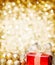 Red Christmas gift with gold baubles and golden background.