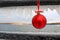 Red Christmas ornament hanging on an ice covered rail