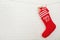 Red Christmas stocking full of gifts hanging on brick wall, space for text.