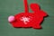 Red Christmas tree decoration in the shape of a rabbit made of felt with ornaments on a green background