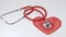 Red and chrome stethoscope with a red lace heart laying on a white background with copy space