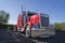 Red classic big rig semi truck with lot of chrome accessories wi