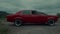 A red classic car starts up and quickly drives off a dusty dirt road, kicking up sand in slow motion