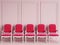 Red classic chairs are standing in an empty pink room with moldings on the wall
