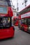 Red classic double decker buses on city road with passengers onboard