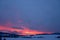 Red clouds at sunrise in winter in the mountains with several houses in the valley, czech beskydy