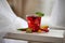 Red cocktail with ice, decorated with mint leaf on light background