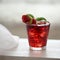 Red cocktail with ice, decorated with mint leaf, lime and trawberry on light background