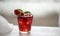 Red cocktail with ice, decorated with mint leaf, lime and trawberry on light background