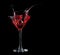Red cocktail splashing into glass on black