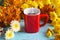 Red coffee cup and colorful flowers on vibrant wooden background