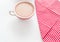 Red coffee cup over kitchen red strips towel. View from above. on white background