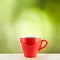 A red coffee cup with steaming on wood desk with top copy space and green nature background refreshment breakfast