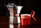 Red coffee cup and vintage coffeepot on dark wooden table