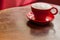 Red coffee mug with frothed milk on an old wooden table