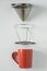 Red coffee mug on white background. Metal pour over drip cone pulled apart