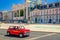 Red color retro vintage car riding in Restauradores Square Praca with Foz Palace Palacio and Teatro Eden building in Lisboa