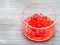 Red colored boiled tapioca balls in bowl on gray