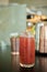 Red colored drink in a tall glass with black pepper celery and lime zest shallow depth of field