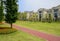 Red-colored path in lawn before fenced houses on sunny summer da