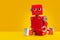 Red colored robot toy leg-split sitting on orange background