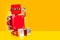 Red colored robot toy sitting on orange background
