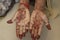 Red colour mehndi design with two hands of girl