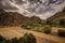 Red coloured river between dry mountains with a bridge and expressive sky in southern Bolivia.