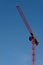 Red construction crane against blue sky