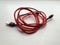 Red cord for charging a smartphone, on a white background. Accessory for phone, USB cable