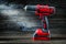 Red cordless drill driver electric screwdriver on vintage wood background