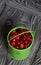 Red cranberries in a miniature green bucket. Stands on brushed boards