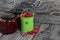 Red cranberries in a miniature green bucket. Stands on brushed boards. Nearby is jars of cranberry jam and some berries scattered