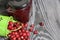 Red cranberries in an overturned green bucket. Lies on brushed boards. Next to it is cranberry jam in a jar