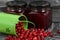 Red cranberries in an overturned green bucket. Lies on brushed boards. Next to it is cranberry jam in a jar