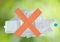 Red cross in front of plastic bag bottle and foam on blur green background