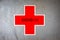 Red cross on worn grey vintage paper background with covid-19 text.