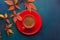 Red cup of black coffee and branch of colorful autumn leaves Virginia creeper on a dark blue-green wooden table. Flat lay