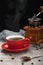 Red cup of black coffee with smoke, grinder and coffee beans on cement table